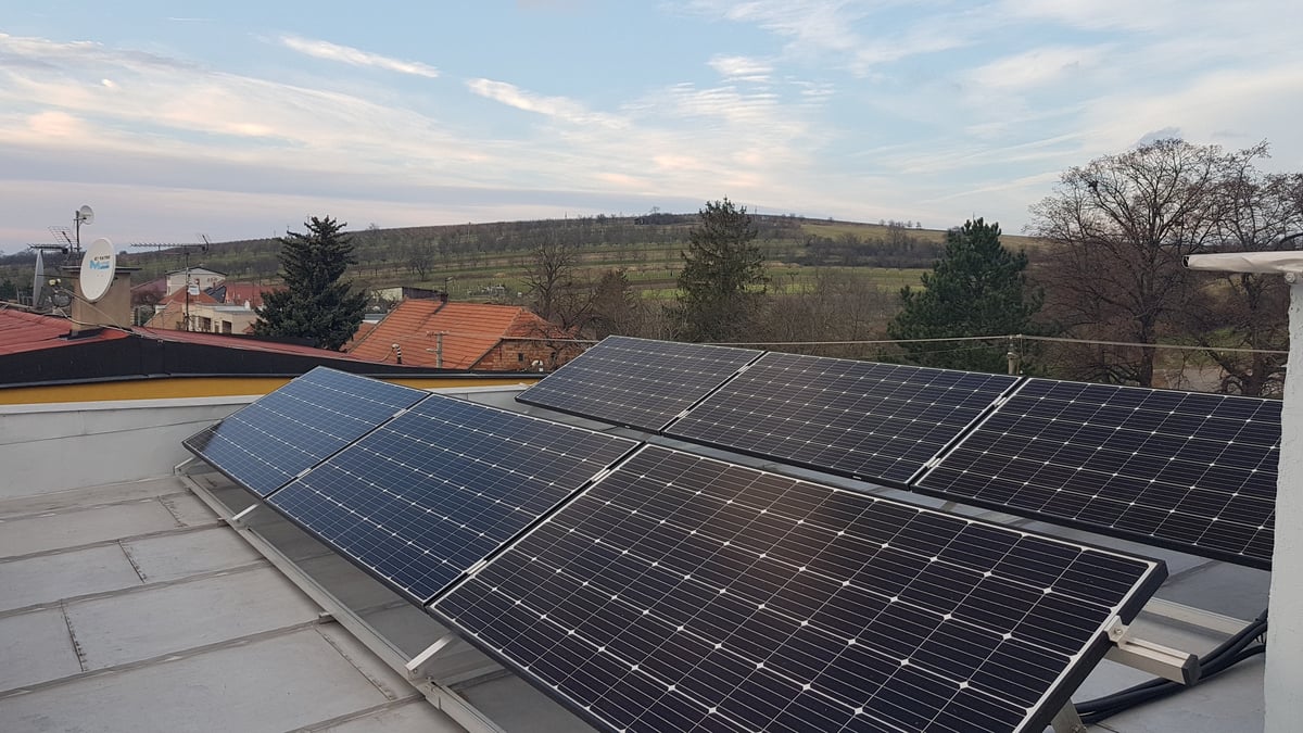 Řada fotovoltaických panelů na konstrukci na ploché střeše
