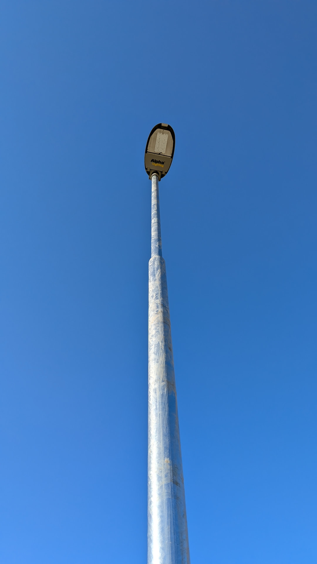 Svítidlo veřejného osvětlení Alpha Lighting na stožáru proti modré obloze